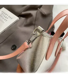 Close-up of metallic silver pleated leather bag with pink straps and silver hardware