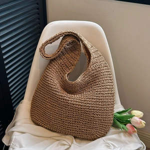 Detailed view of handwoven brown straw hobo bag with natural fiber texture and wide strap