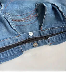 Close-up of blue denim bag with orange contrast stitching and vintage silver metal buttons