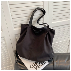 Detail view of a large black canvas tote bag with long leather straps for shoulder carry