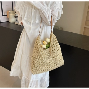 Detail view of woven straw tote bag with brown faux leather straps and crochet pattern