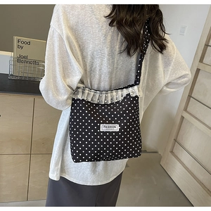 Dettaglio della borsa a secchiello in nylon a pois con balza in pizzo e perle applicate
