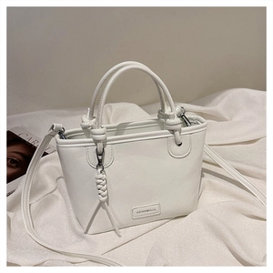 Détail d'un sac à main blanc avec poignée nouée et plaque de logo de marque élégante