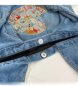Détail du cabas en denim avec broderie de dragon et fermeture à bouton métallique