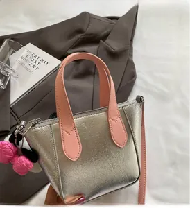 Detail of silver tote bag with pink handles and bow charm on a stylish brown suit