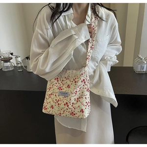 Lace trim and pearl detail on a floral nylon bucket bag shown in a cafe setting