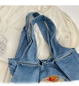 Gros plan sur un sac cabas en jean vintage avec broderie florale et larges poignées
