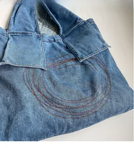 Detail of blue denim fabric featuring intricate brown circular embroidery and washed texture