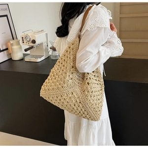 Detail of handwoven straw tote bag with brown leather strap and hollow-out texture