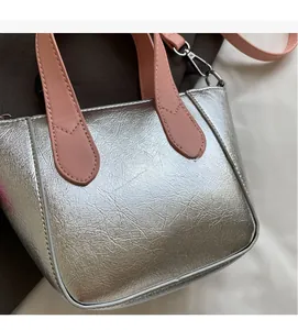 Detail view of silver cracked leather texture and pink handle on stylish bucket bag