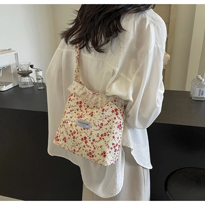 Detail of floral canvas crossbody bag with lace trim and pearls on a model