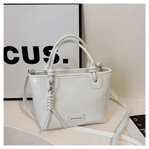 Détail du sac seau en cuir PU blanc avec nœuds de poignée tressés et étiquette de marque