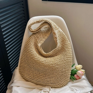 Detail of hand-woven straw shoulder bag with hollow crochet texture and beige fabric lining