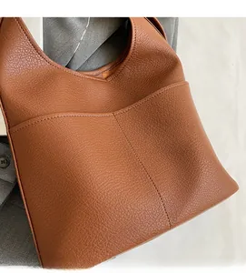 Detail of warm brown lychee grain leather tote bag showing texture and front pocket
