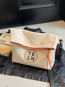 Canvas tote bag with vibrant orange zipper detail over black jacket, casual style