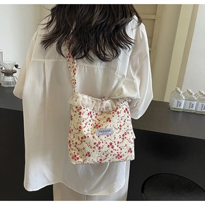 Detail of floral nylon bucket bag featuring lace edges, pearl accents and logo patch