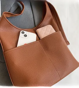 Close-up of brown pebbled leather tote featuring a front pocket with phone and card holder