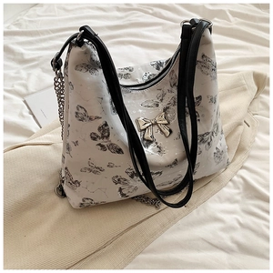 Detailed close-up of white butterfly print tote bag with golden bow clasp and metal chain