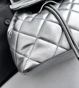 Detail van zilveren gewatteerde tas met trekkoord en zachte metallic textuur