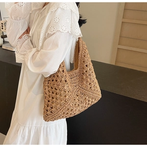 Detail of hollow woven texture on khaki straw tote bag with integrated shoulder strap