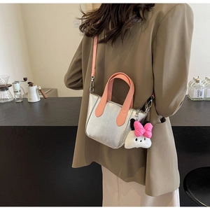 Detail showing metallic silver handbag with pink straps and a cute plush bunny pendant