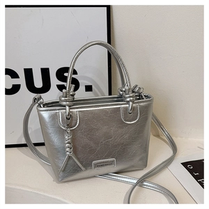 Détail du sac seau argenté avec texture métallisée froissée et breloque tressée