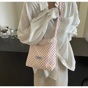 Detail of polka dot nylon bucket bag with lace trim and pearls in a modern cafe setting