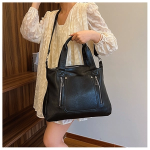 Close-up of the large black leather tote bag featuring functional zippers and large pocket