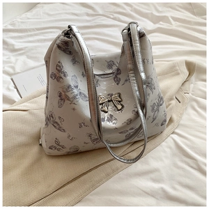 Detail of silver butterfly print tote bag featuring a metallic 3D bow and dual straps