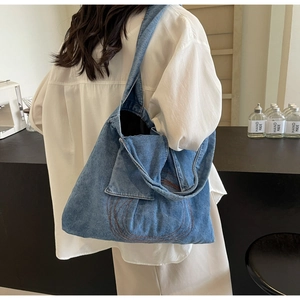 Detail of blue denim tote bag featuring vintage spiral embroidery and square front pocket