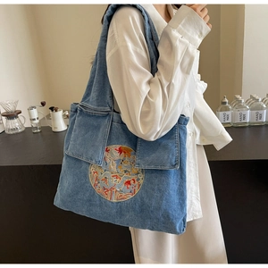 Détail du sac cabas en denim bleu avec broderie traditionnelle et deux poches avant