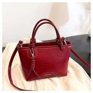 Gros plan sur un sac seau bordeaux en similicuir texturé avec plaque de marque
