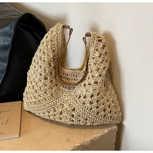 Detail of hand-woven straw tote bag with retro hollow pattern and leather handles