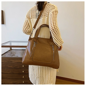 Model wearing a large dark brown faux leather tote bag with stylish vertical zippers