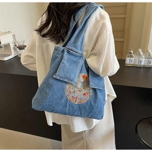 Détail d'un sac cabas en denim bleu avec broderie circulaire et poche avant pratique
