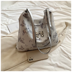 Detail of grey butterfly print tote bag with silver bow buckle on soft fabric background