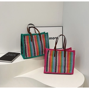 Detailed view of colorful woven straw tote bags with vertical stripes and leather handles