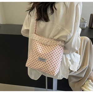 Dettaglio borsa a secchiello in nylon bianco a pois rossi con pizzo e perle