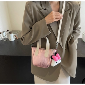 Detail of pink metallic textured bucket bag with plush charm and adjustable strap