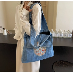 Détail d'un sac cabas en denim délavé bleu avec un écusson brodé rond de style ethnique