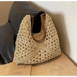 Detailed close-up of the hollow crochet weave and leather handles of the woven tote bag