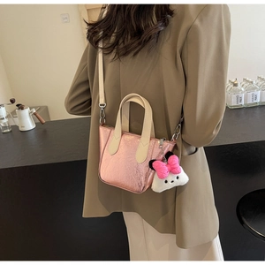 Pink metallic pleated tote bag with beige straps and cute plush charm on a model