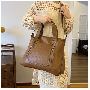 Close-up of brown textured leather tote bag with functional vertical zipper pockets