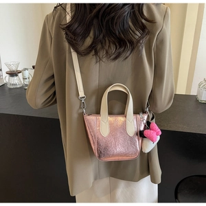 Detail of metallic pink bucket bag with cream handle and cute bow charm accessory