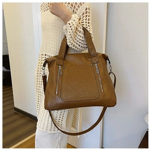 Detail of tan tote bag with dual zippers, faux leather texture and crossbody strap