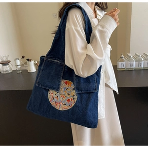Détail du sac cabas en denim avec broderie dragon et grandes poches plaquées à l'avant