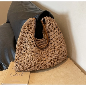 Detailed view of hollow woven texture and brown leather handles on a straw tote bag