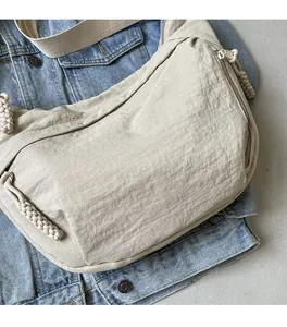 Detail of beige nylon crescent bag featuring wrinkled texture and fabric shoulder strap