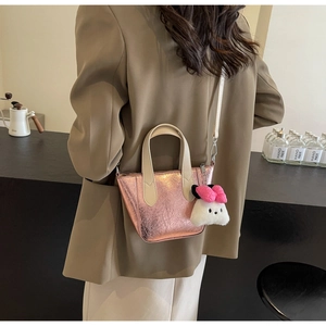 Detail of metallic pink wrinkled bucket bag featuring a plush bunny charm on white handle