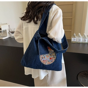 Détail du grand sac cabas en denim bleu avec broderie circulaire et bandoulière large